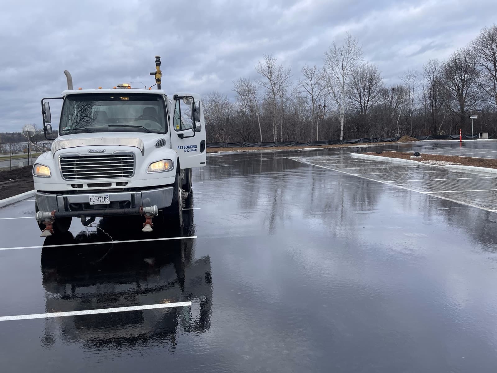 Soak N Wet truck applying water to a paved lot for dust control